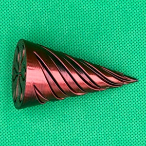 May include: A metallic red, conical object with a spiraling, grooved texture along its length. The flat, circular base features a recessed, symmetrical four-petal flower design. The object tapers to a pointed tip, showcasing a smooth finish.