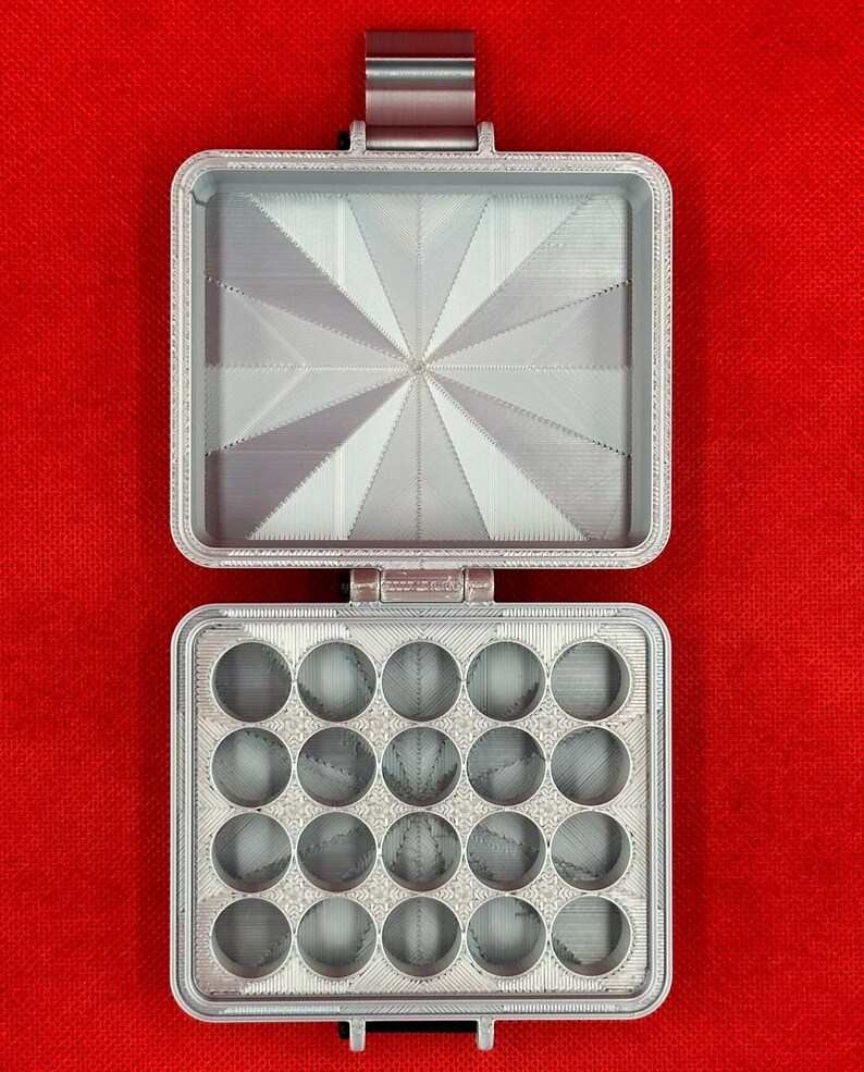 May include: A light grey, rectangular, 3D-printed storage case with a hinged lid. The interior of the lid features a sunburst pattern, while the base contains twenty circular compartments arranged in a four-by-five grid for small items.