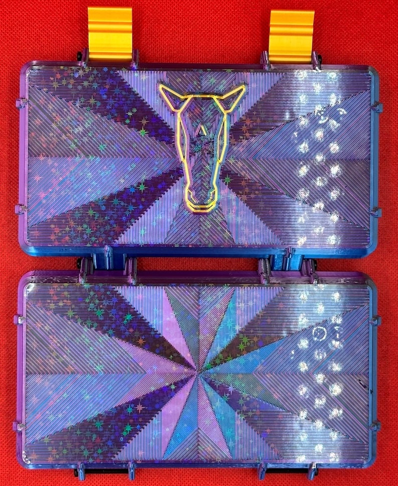 May include: Two purple and blue iridescent plastic cases with a starburst pattern. The top case has a gold outline of a horse's head.