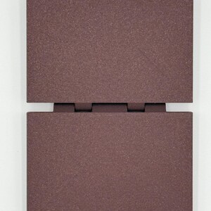 May include: Two rectangular, dark brown panels connected by hinges. The panels have a textured surface and are positioned vertically, with one panel slightly above the other. The color is a deep, earthy tone, suggesting a natural material.