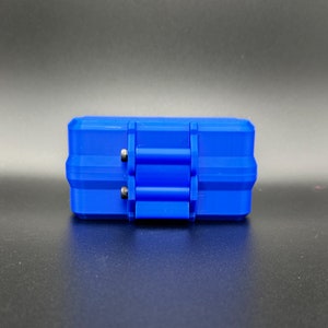 May include: A rectangular blue storage case featuring a hinged lid with a central latch mechanism. The case has a textured, rigid exterior with two small silver-colored metal pins visible on the side of the hinge assembly.