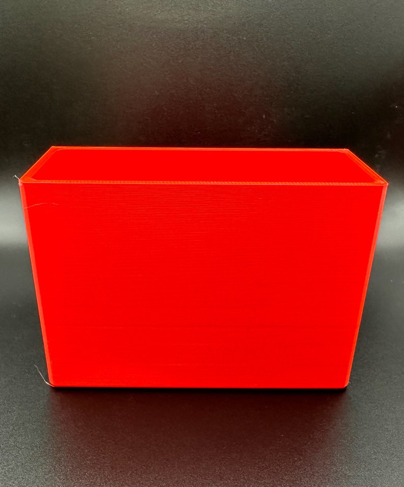 May include: A bright red rectangular plastic container. The container is empty and has a smooth surface.