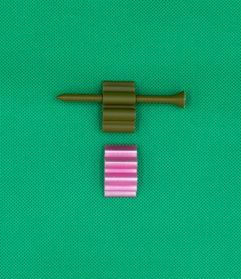 May include: A green golf tee with a pink striped golf ball holder.