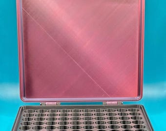 May include: A rectangular storage case with a metallic red lid and a black base. The interior of the base features a grid of numerous circular compartments designed for organizing small items. The case has two red latches on the top edge.