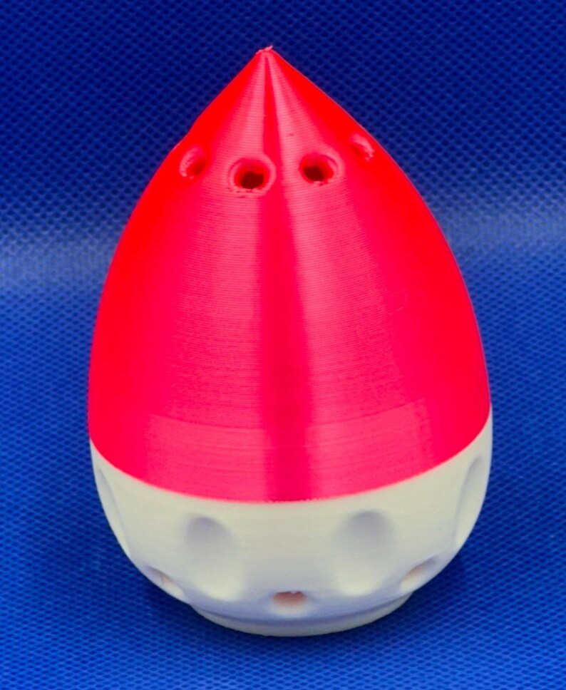 May include: A pink and white 3D printed object shaped like a teardrop with holes on the top and bottom.