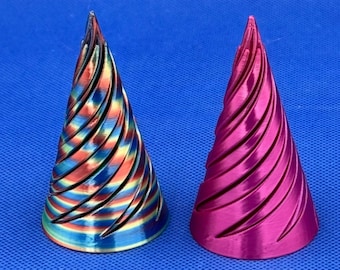 May include: Two conical objects with a spiraling, ribbed texture. The object on the left features a multi-colored, iridescent gradient of blue, gold, and red. The object on the right is a solid, metallic magenta color with a smooth, glossy finish.