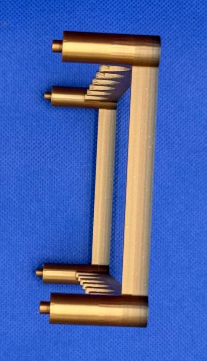 K&ouml;nnte beinhalten: Ein goldfarbener Plastikst&auml;nder mit rechteckiger Form und einem Gittermuster oben und unten. Der St&auml;nder hat vier Beine.