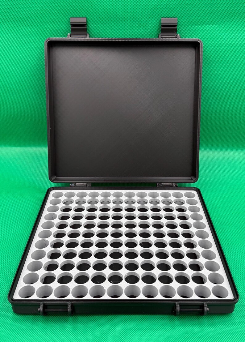 May include: Black plastic storage case with a white foam insert containing 100 round compartments. The case is open and the lid is propped up.