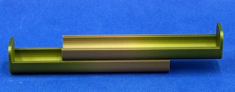 May include: Two stacked, green, metal, rectangular containers with rounded edges. The containers are open on one side and have a slight gradient of color from dark green to light green.