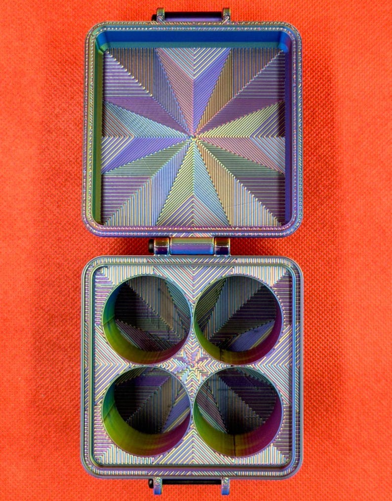 May include: A metallic iridescent box with four compartments. The box is open and the inside is lined with a geometric pattern.