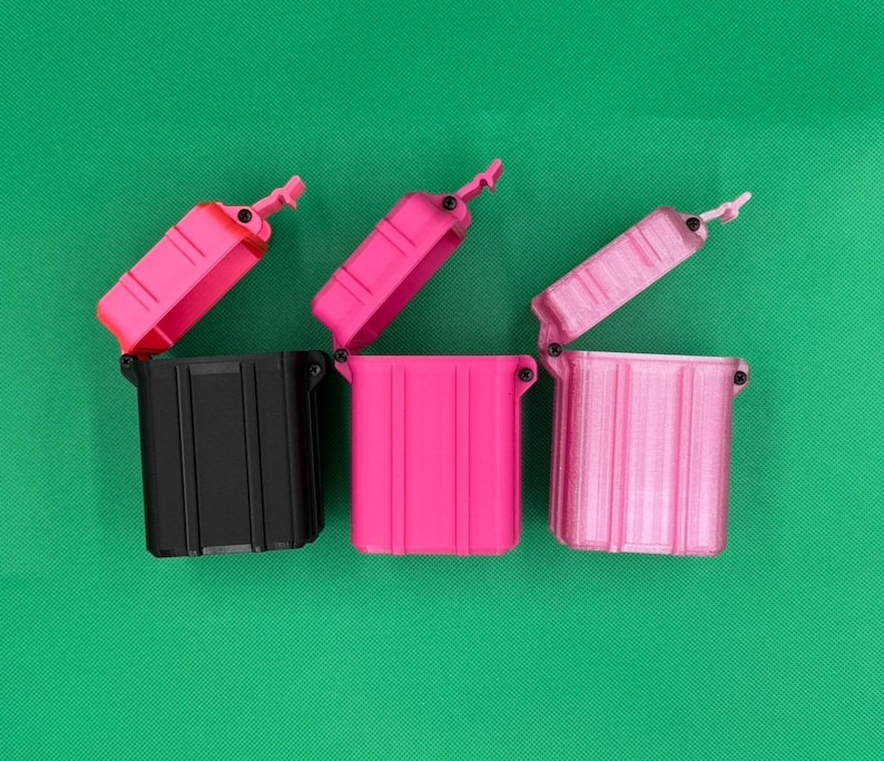 Puede incluir: Tres contenedores de almacenamiento rectangulares con tapas abatibles en posici&oacute;n abierta. El primer contenedor es negro, el segundo es rosa brillante y el tercero es de un tono rosa m&aacute;s claro. Cada estuche tiene ranuras verticales.