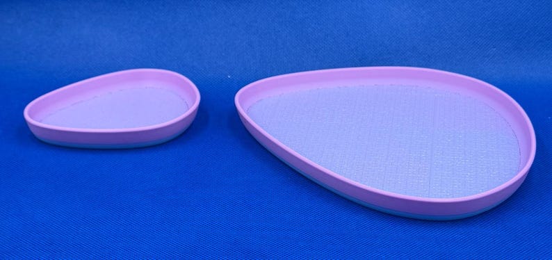 May include: Two pastel purple oval-shaped trays with a light blue rim. The smaller tray is on the left and the larger tray is on the right.