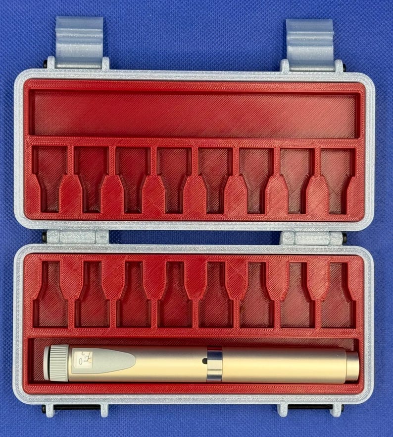 May include: A rectangular storage case with a light gray exterior and a red interior featuring molded slots for small items. One gold-colored cylindrical pen-like tool with a white dial and a small digital display is placed in the bottom row.