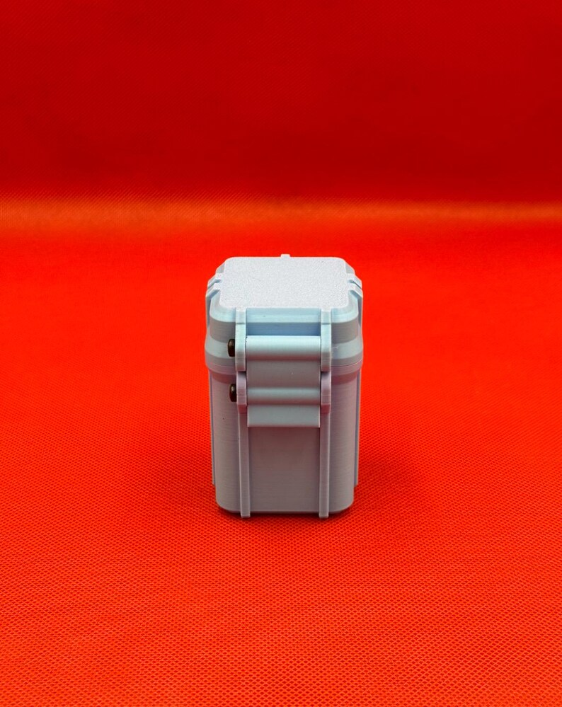 May include: A light blue, rectangular, hard-shell storage case with a textured top surface and a vertical latch mechanism on the side. The container features a solid, matte finish and a structured, boxy design with rounded corners.