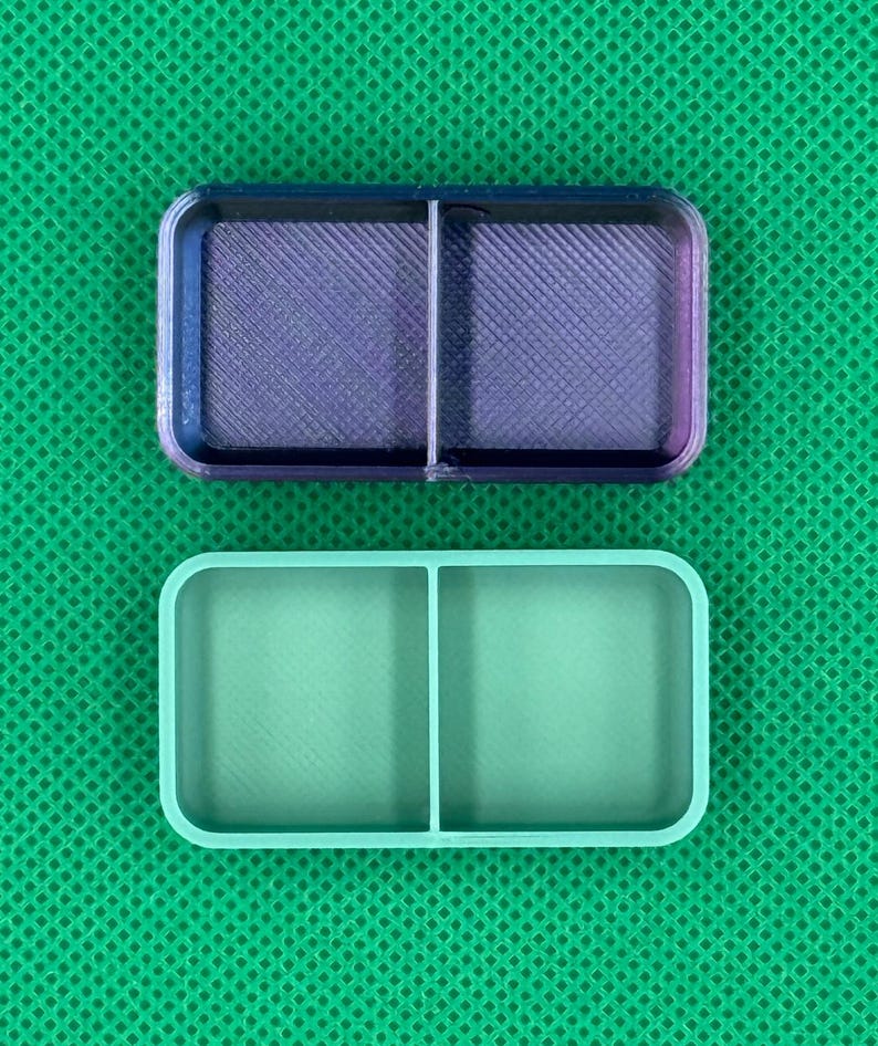 May include: Two rectangular, divided containers. The top container is a gradient of purple and blue, with a crosshatch pattern. The bottom container is a solid light green color. Both containers have rounded corners.