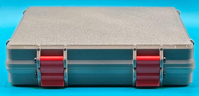 May include: A gray plastic storage case with two red latches. The case has a textured surface and is closed.