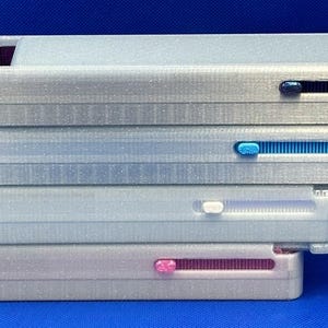 May include: Four stackable, white plastic storage boxes with different colored sliding latches. The top box has a black latch, the second box has a blue latch, the third box has a white latch, and the bottom box has a pink latch.