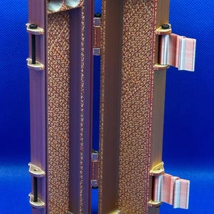 May include: A small, rectangular, brown, 3D printed case with a hinged lid. The case is open, revealing an empty interior. The case has a textured surface and a small hole on the inside of the lid.