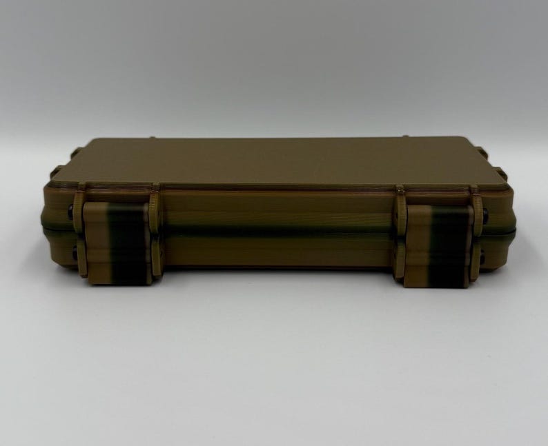 May include: A rectangular, tan-colored hard-shell storage case with a smooth, flat top surface. The case features two dark brown, vertical locking latches on the front edge, designed to secure the lid firmly to the base of the container.
