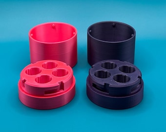 May include: Two cylindrical containers with matching lids, one in bright pink and one in dark purple. Each lid features four circular openings and a notched edge, while the matching base components are open-ended cylinders.