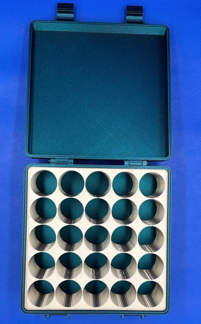 May include: A teal green plastic storage case with a hinged lid and 24 round compartments. The case is open and the compartments are empty.