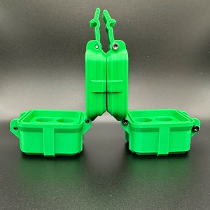 Puede incluir: Un estuche de almacenamiento verde brillante impreso en 3D con dos compartimentos abiertos, cada uno con dos hendiduras circulares interiores. El estuche tiene un mecanismo de tapa con bisagras y pesta&ntilde;as de bloqueo verticales.