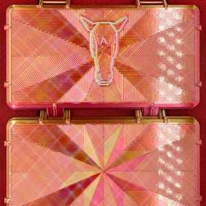 May include: Two gold-toned metal plates with a geometric pattern. The top plate features a stylized horse head design.