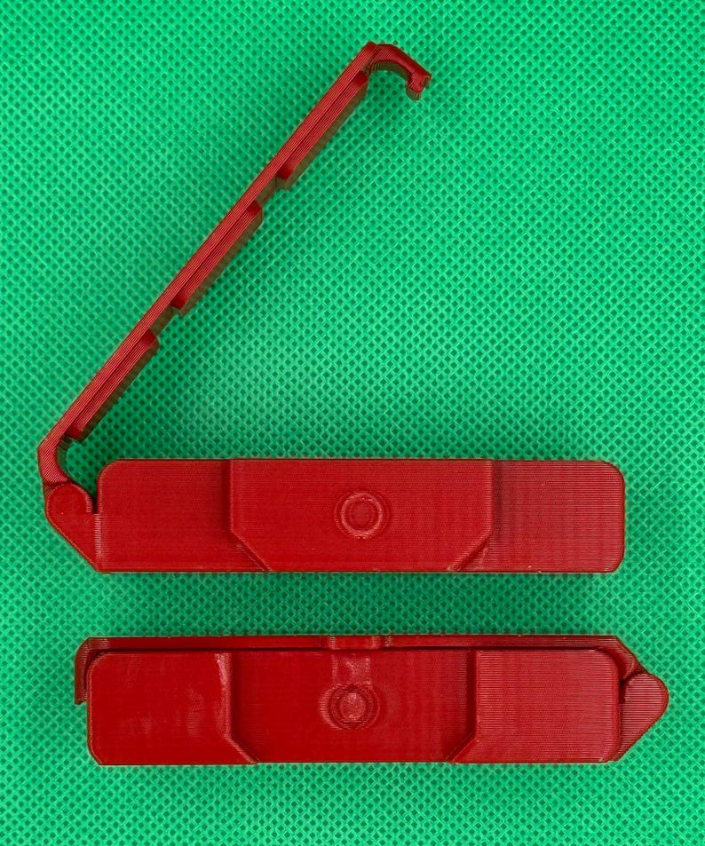 Puede incluir: Dos piezas de pl&aacute;stico rojo que encajan para formar una peque&ntilde;a caja rectangular. La caja tiene un peque&ntilde;o agujero redondo en el centro de la parte superior.