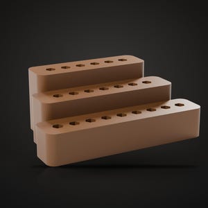 May include: A tiered light brown display stand featuring three levels, each with a row of six hexagonal holes along the top surface. The structure has rounded edges and a smooth, matte finish, arranged in a stepped formation for organized storage.