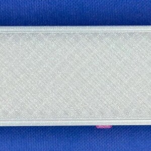 May include: A rectangular sliding case with a textured silver exterior and a bright pink interior. The case is partially open, revealing a small, clear plastic syringe with a vibrant orange cap resting inside the pink compartment.