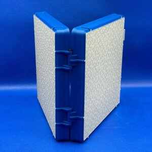 K&ouml;nnte beinhalten: Ein blauer, klappbarer Aufbewahrungskasten mit einem wei&szlig;en, strukturierten Innenraum. Der Kasten ist geschlossen und steht aufrecht auf einer blauen Oberfl&auml;che.
