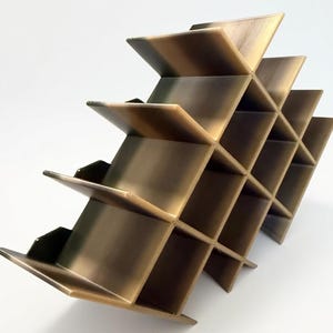 Puede incluir: Un botellero de metal color bronce con un dise&ntilde;o de rejilla geom&eacute;trica y m&uacute;ltiples compartimentos cuadrados. La estructura est&aacute; compuesta por paneles que se cruzan creando una serie de espacios abiertos para botellas.