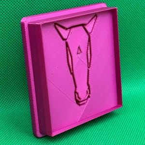 K&ouml;nnte beinhalten: Eine rosa 3D-gedruckte Form mit einem geometrischen Pferdekopf-Design.
