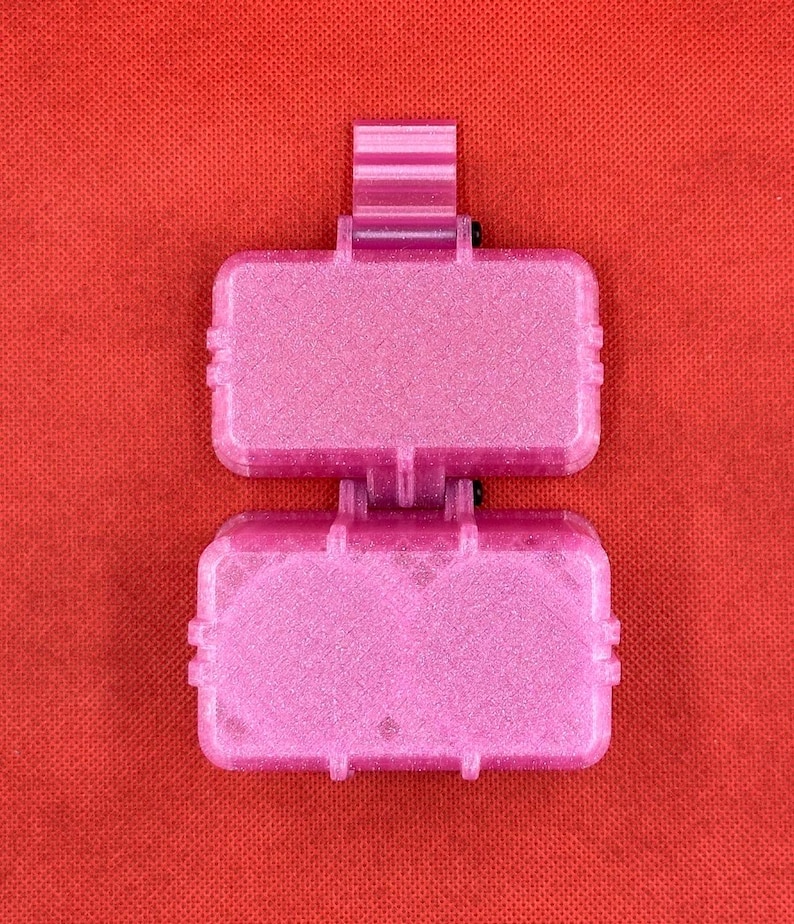 May include: Two pink plastic containers with a sparkly finish. The containers are stacked on top of each other. The top container has a small handle.