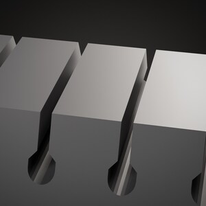 Op de afbeelding: Een grijs industrieel onderdeel met een reeks parallelle rechthoekige blokken gescheiden door diepe, smalle verticale sleuven die eindigen in afgeronde, cilindrische openingen aan de basis, wat een uniform, herhalend geometrisch patroon cre&euml;ert.