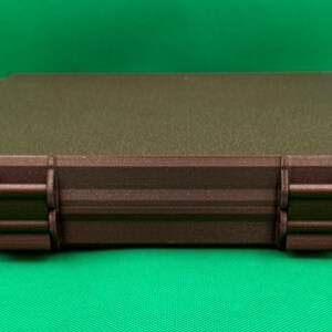 May include: A brown rectangular storage case with two latches on each side. The case has a textured, speckled surface.