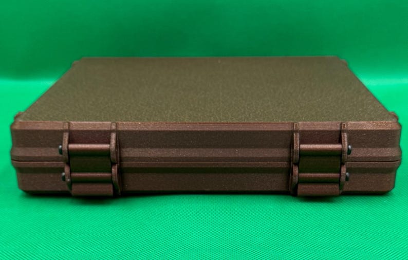 May include: A brown rectangular storage case with two latches on each side. The case has a textured, speckled surface.
