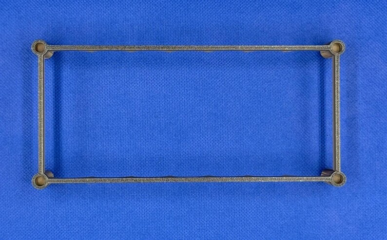 K&ouml;nnte beinhalten: Ein grauer Metallrahmen mit abgerundeten Ecken. Der Rahmen befindet sich auf einem blauen Hintergrund.
