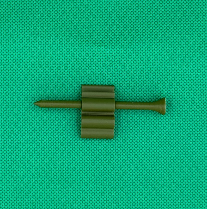May include: A green plastic golf tee with a pointed end and a ribbed body.
