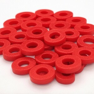May include: A pile of bright red plastic rings, stacked and scattered on a white surface.