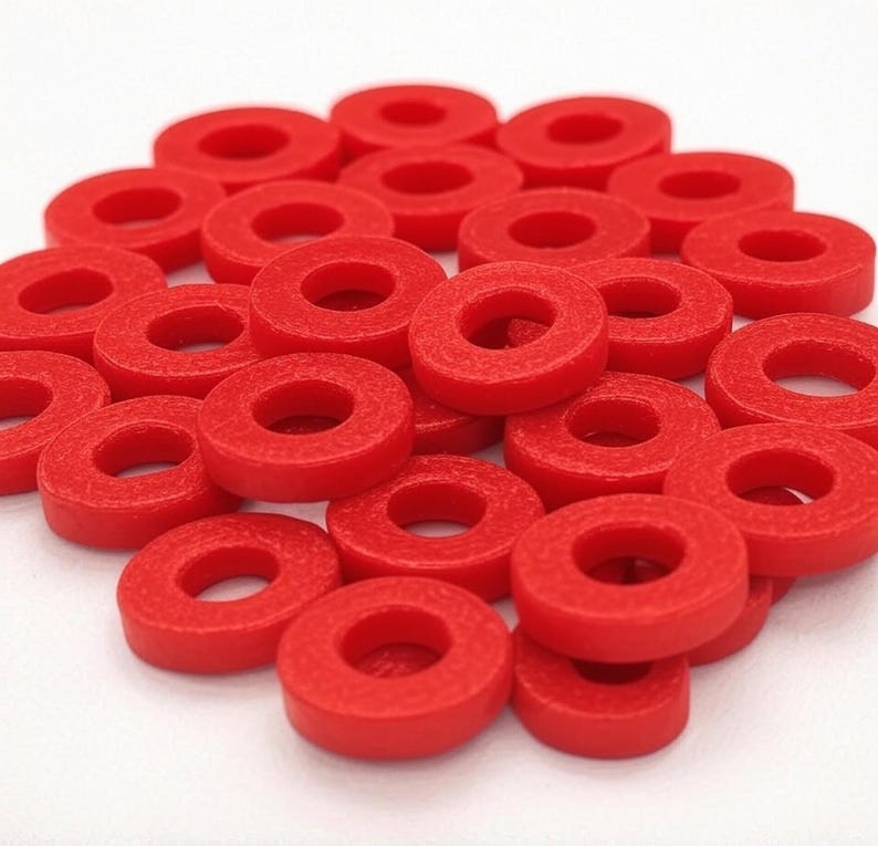 May include: A pile of bright red plastic rings, stacked and scattered on a white surface.