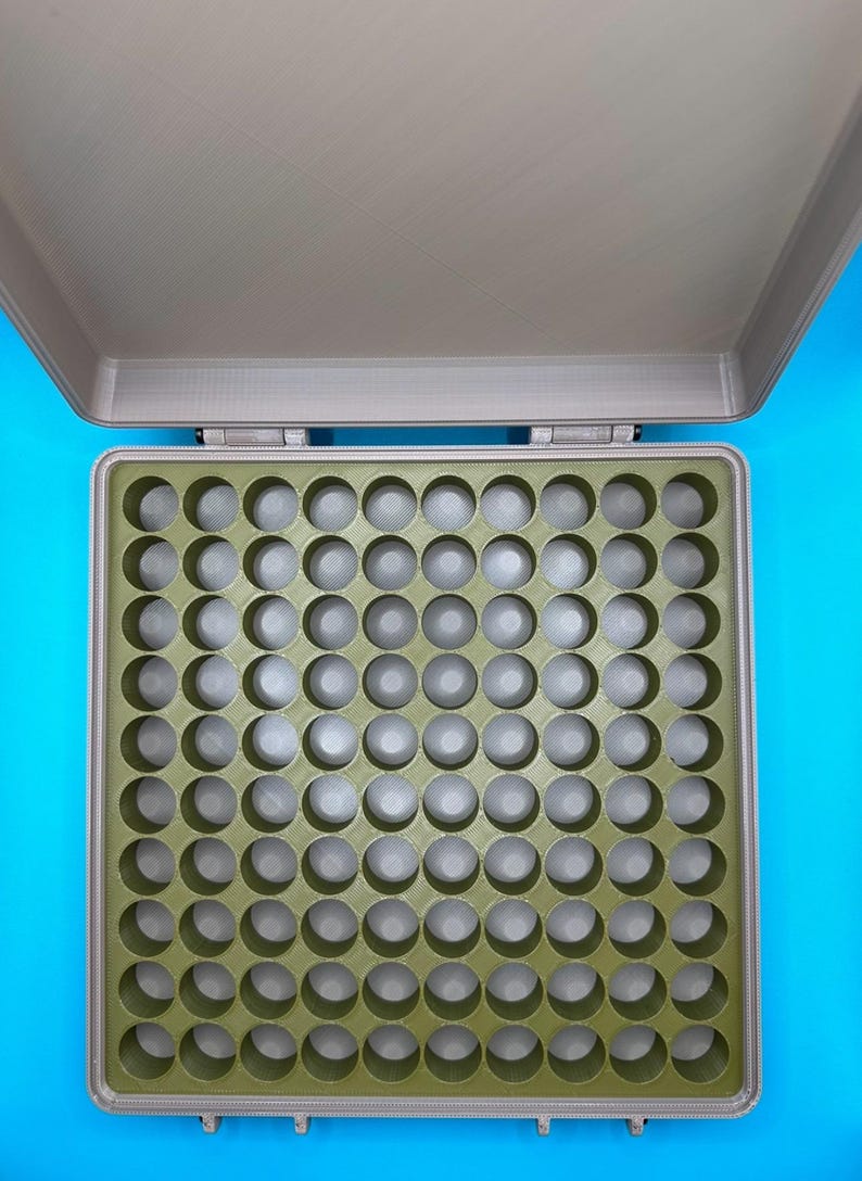 May include: A gray plastic storage case with a green foam insert. The insert has 64 round compartments.