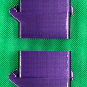 Puede incluir: Dos cajas de plástico morado con cierre a presión y tapa con bisagra. Las cajas están apiladas una encima de la otra.