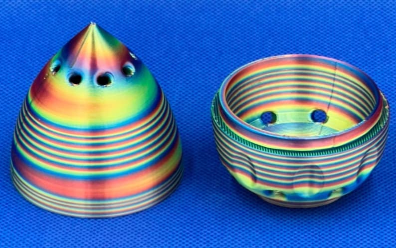 May include: Two 3D printed objects, a cone and a bowl, with a rainbow iridescent finish. Both objects have multiple holes in the top.