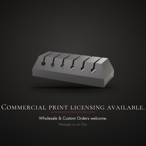 Op de afbeelding: Een grijs, rechthoekig kabelorganizerblok met vijf gelijkmatig verdeelde verticale sleuven met cirkelvormige openingen aan de basis. De tekst luidt: COMMERCIAL PRINT LICENSING AVAILABLE. Wholesale & Custom Orders welcome. Message us on Etsy.