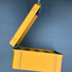 May include: A yellow plastic storage box with a hinged lid. The lid is open and the box is empty.