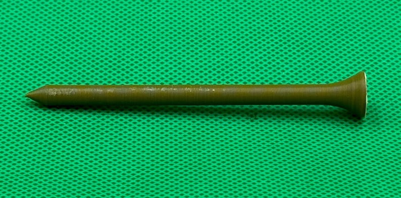May include: A long, thin, brown metal nail with a pointed tip and a flared head.