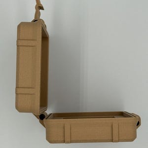 Puede incluir: Caja rectangular abierta de color beige con tapa abisagrada. La caja tiene una superficie texturizada y un peque&ntilde;o asa en la parte superior. La caja est&aacute; dise&ntilde;ada para proteger objetos.