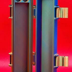 May include: A metallic blue and gold storage case with a hinged lid. The case has two small circular compartments on one side and a long, rectangular compartment on the other side.
