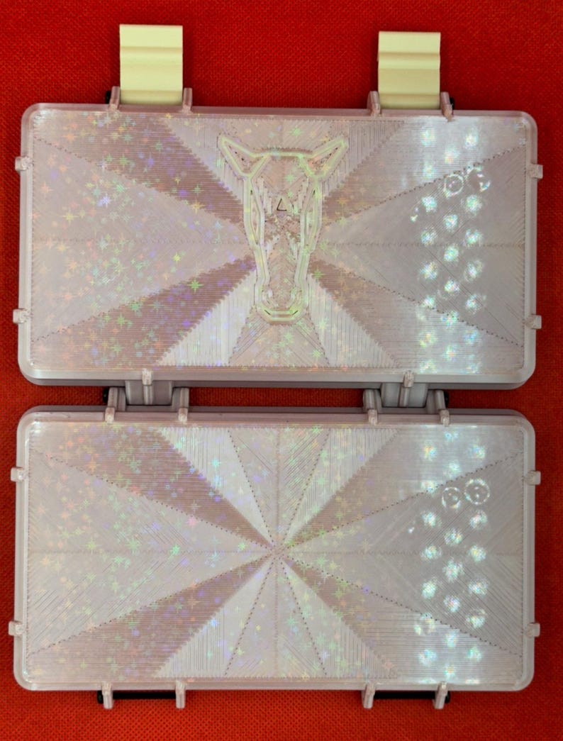 May include: Two iridescent white plastic boxes with a geometric pattern and a horse head design. The boxes are closed and have a hinge on the side.
